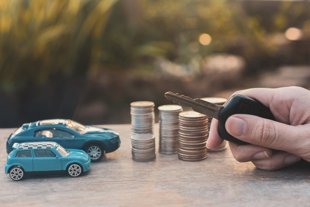 hand-holding-key-of-car-and-model-coins-stack-on-wooden-table-finance-insurance-and-transportation_t20_nRO606 - Fabre de Nombel Assurances